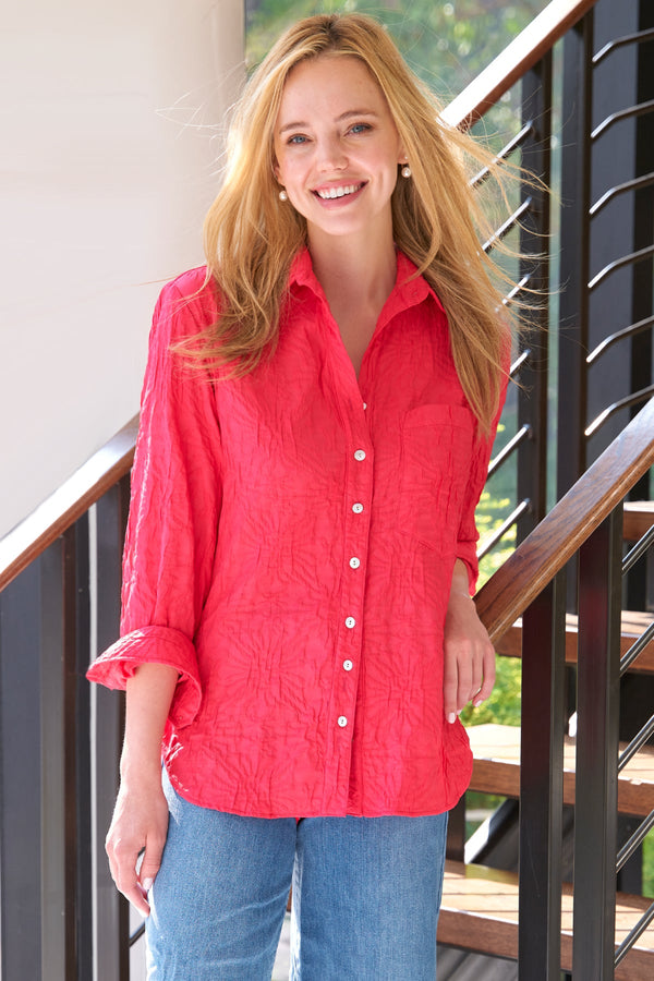 A model wearing the Finley Andie blouse, a cotton button down raspberry pink blouse with a relaxed contour and barrel cuffs