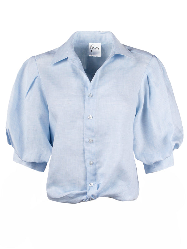 A front view of the Finley bomba blouse, a relaxed fit blue chambray linen blouse with elbow blouson sleeves and a front-twist hem.