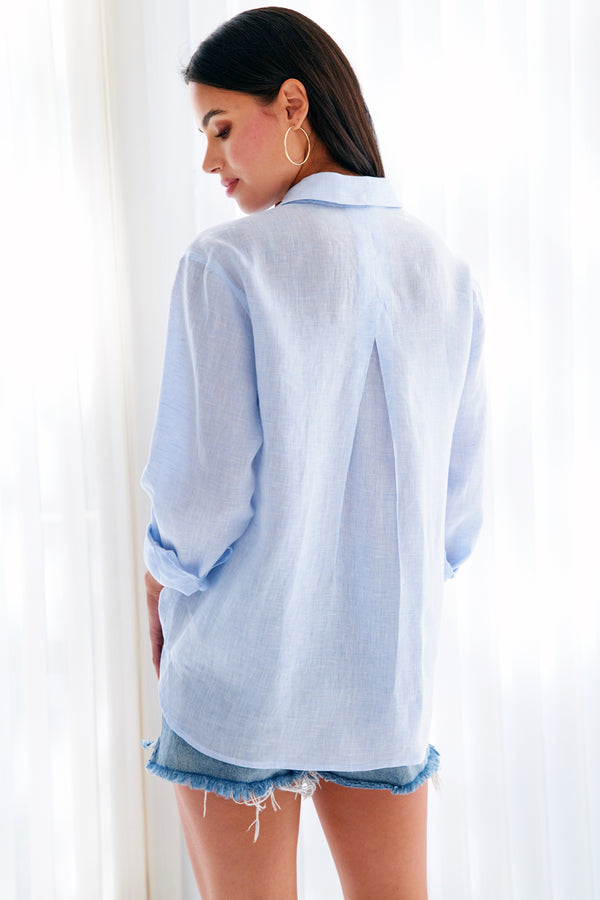A rear view of the Finley Niko blouse, a pale blue chambray linen boyfriend shirt with a chest pocket and a relaxed fit.