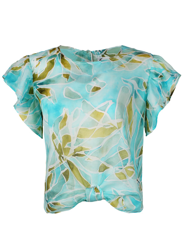 A front view of the Finley knot top, a cotton voile popover blouse with a knotted hem and a pale blue tropical print.