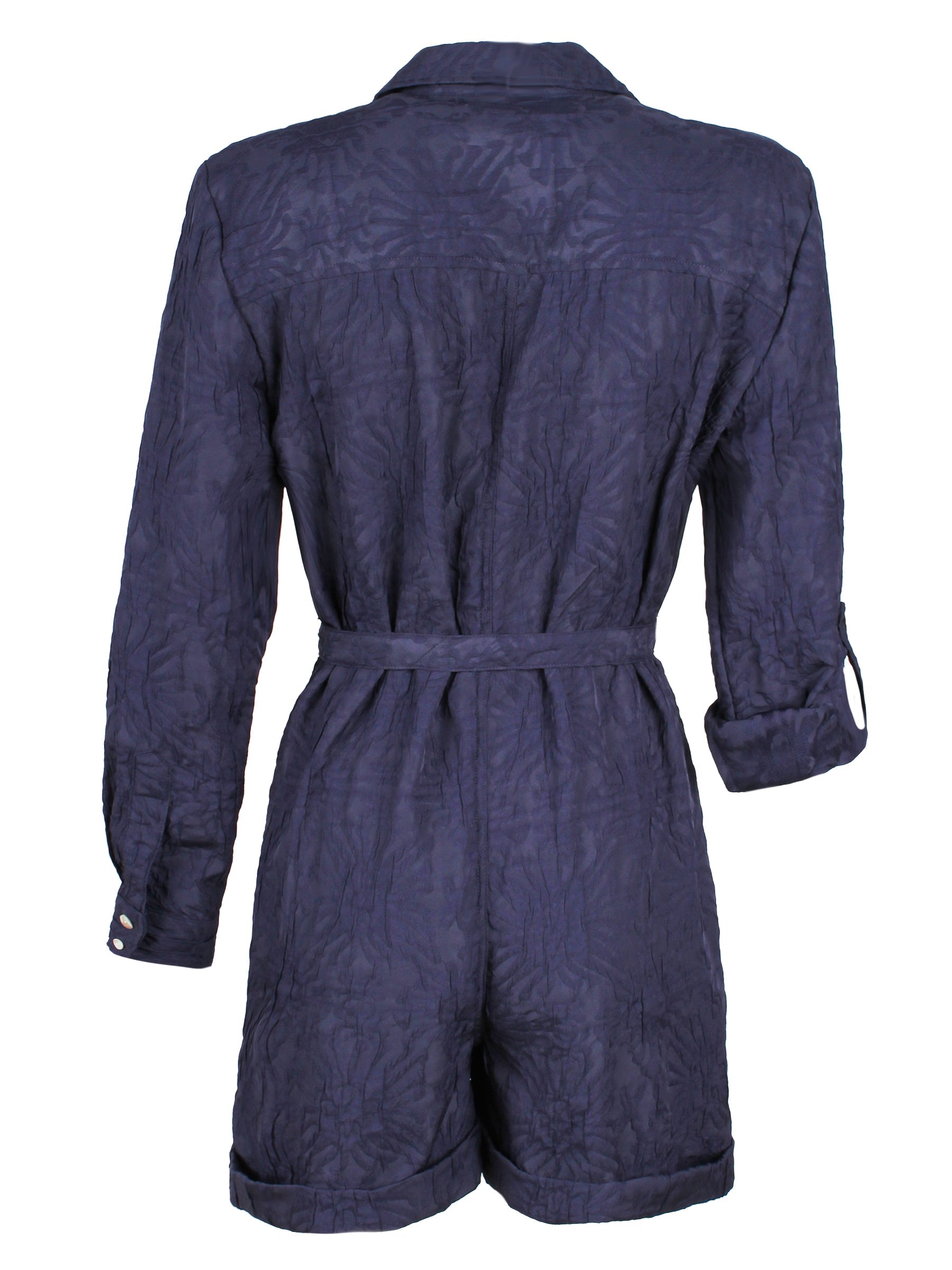A rear view of the Finley Romper, a raspberry pink jacquard one-piece button down romper with a tie front and barrel cuffs.