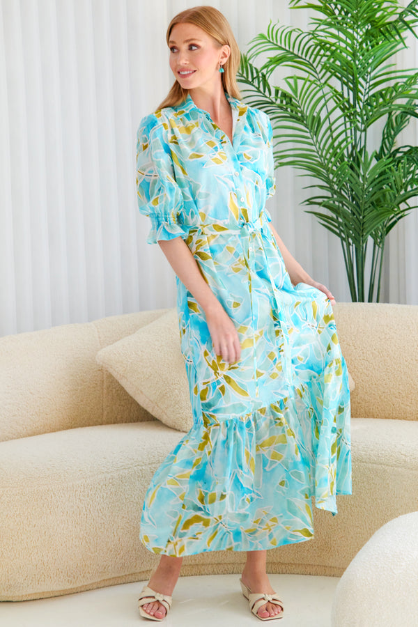 A model wearing the Finley Sienna dress, a cotton voile tie-front maxi dress with smocked cuffs and a tropical watercolor print.