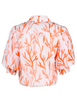 A rear view of the Finley Bomba blouse, a button-down ladies blouse with elbow blouson sleeves, a front-twist hem, and an orange coral watercolor print.