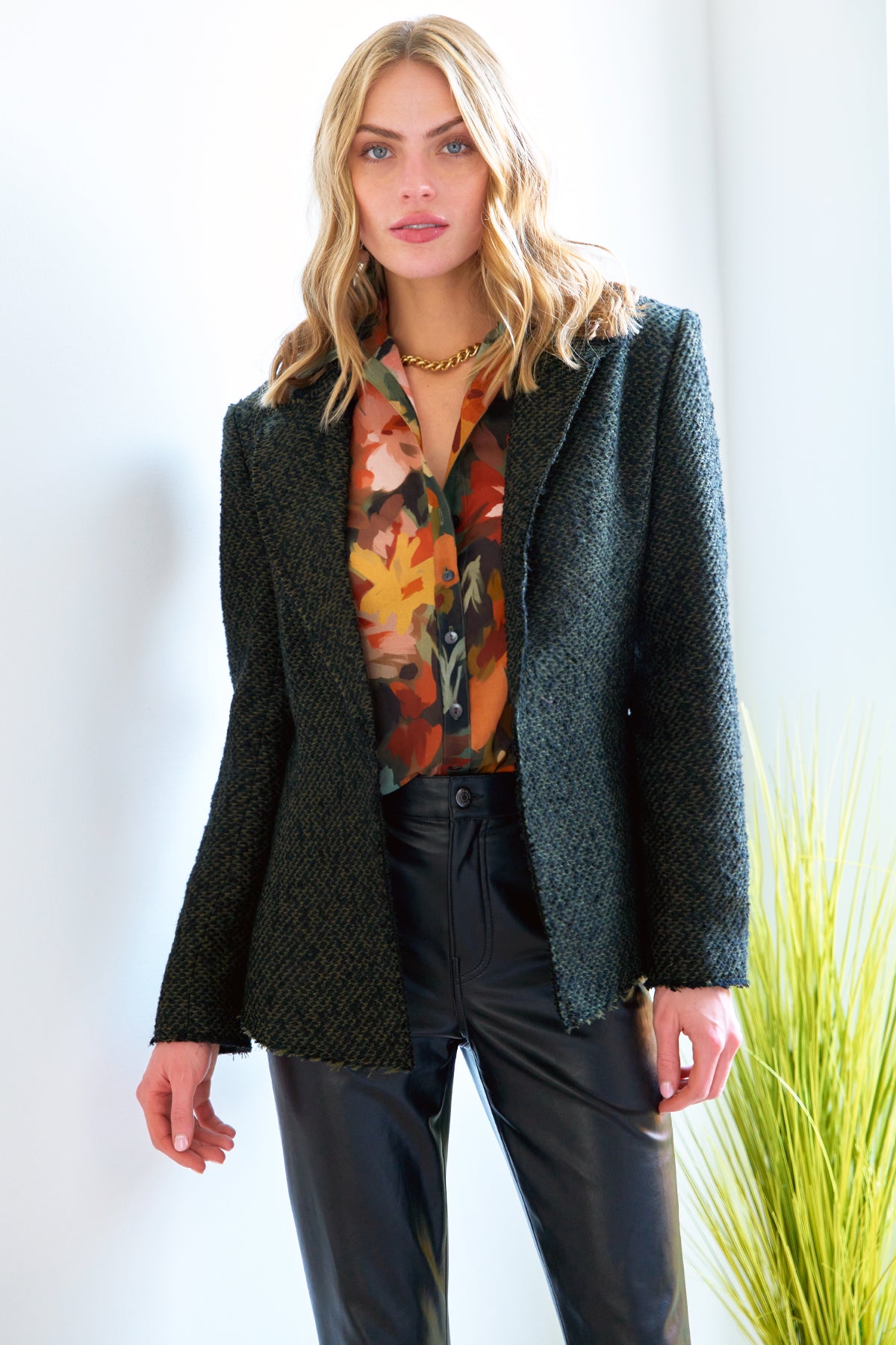 A model wearing the Baxter tweed jacket, featuring a blazer style, notched collar, and an olive & black color combination with a semi-fitted cut.