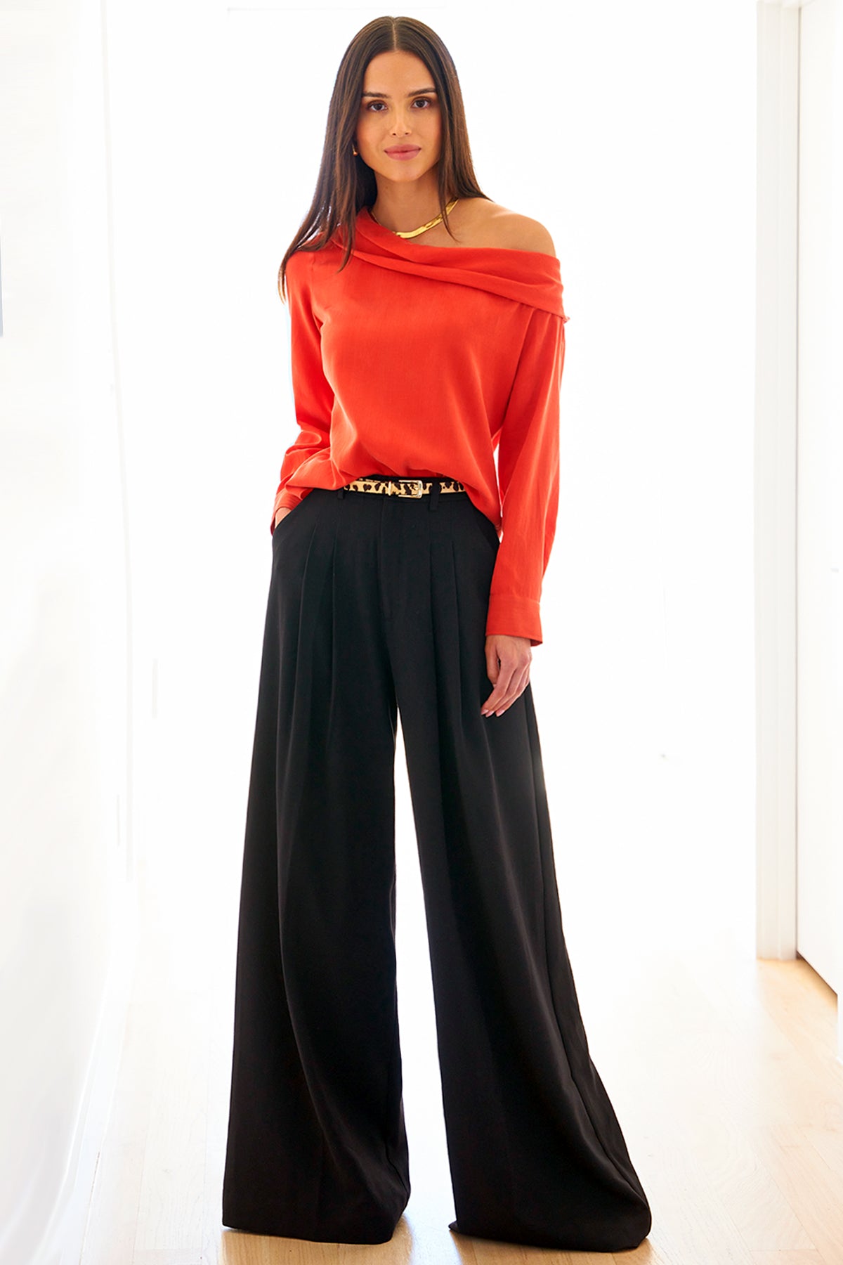 A back view of the Dani shirt, featuring long sleeves, an off-shoulder foldover neckline, cupro cotton fabric in flame red, and a relaxed shape.