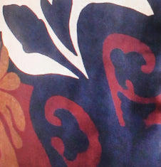 A close-up of a patterned fabric or material featuring abstract organic shapes in navy blue, red, white, and a small tan area.