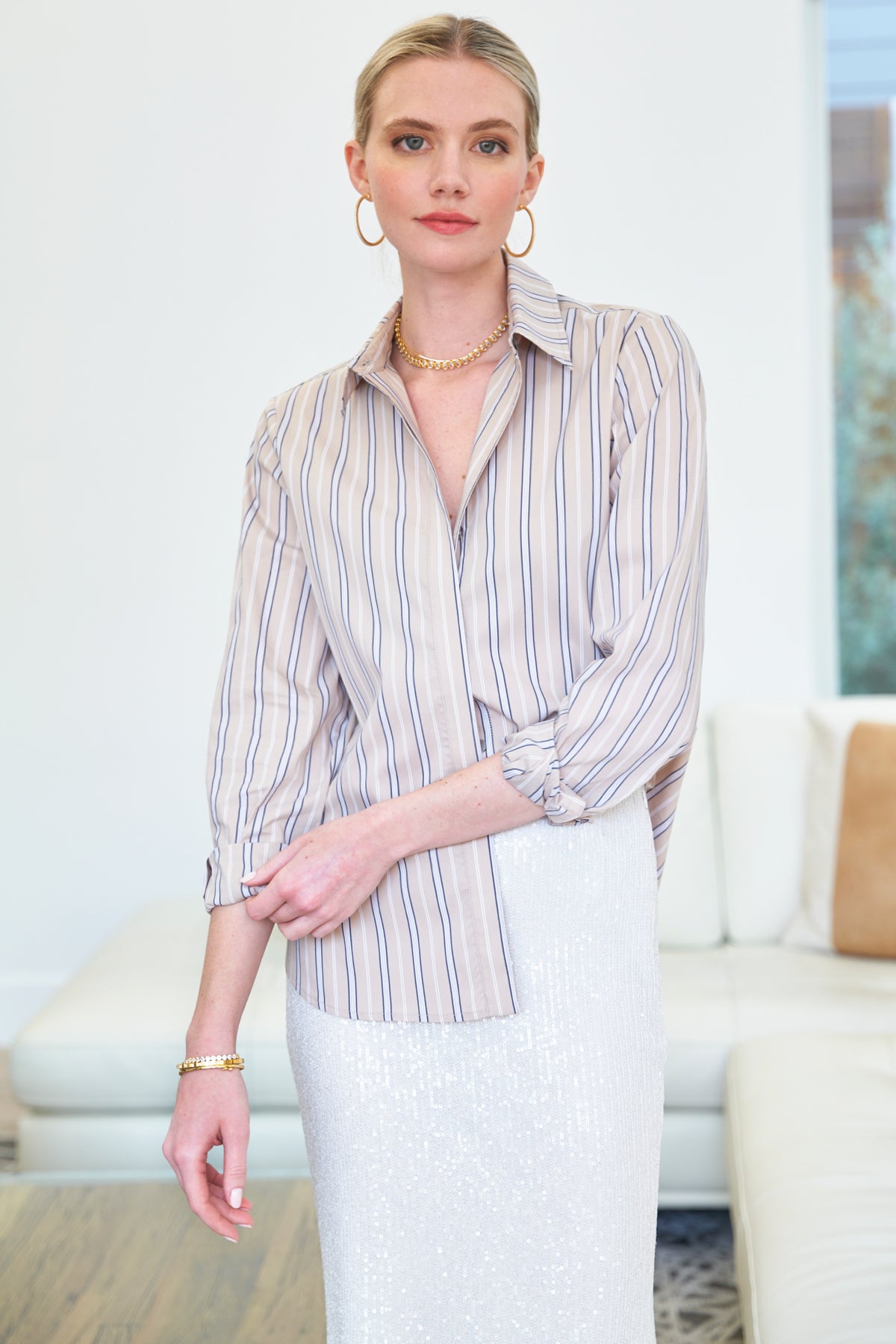 A model wearing the Mason blouse, featuring tan, black & white stripes, a relaxed fit, rounded hem, and long sleeves.