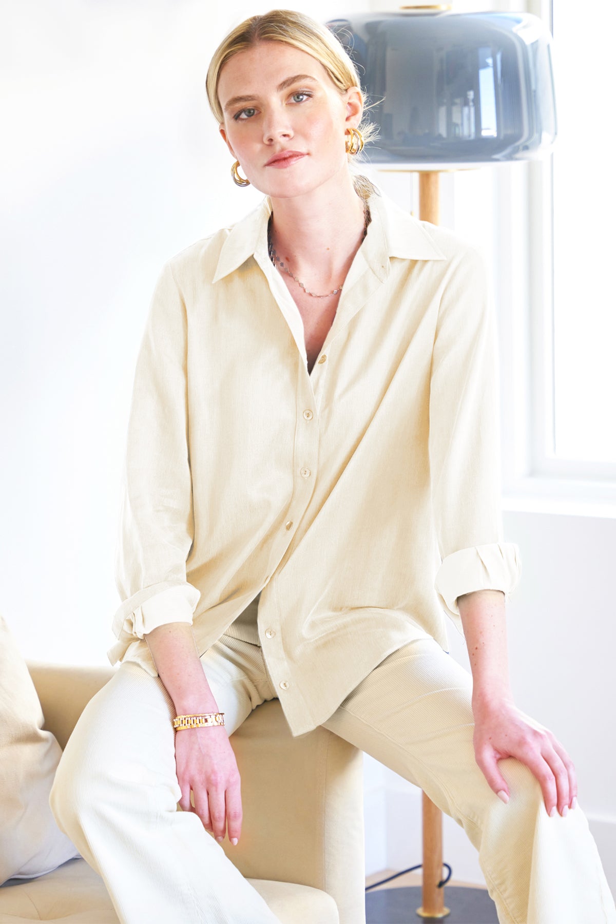 A model wearing the Mini Monica shirt, crafted from cupro and cotton in cream, featuring a spread collar, relaxed fit, shirttail hem, and long sleeves.