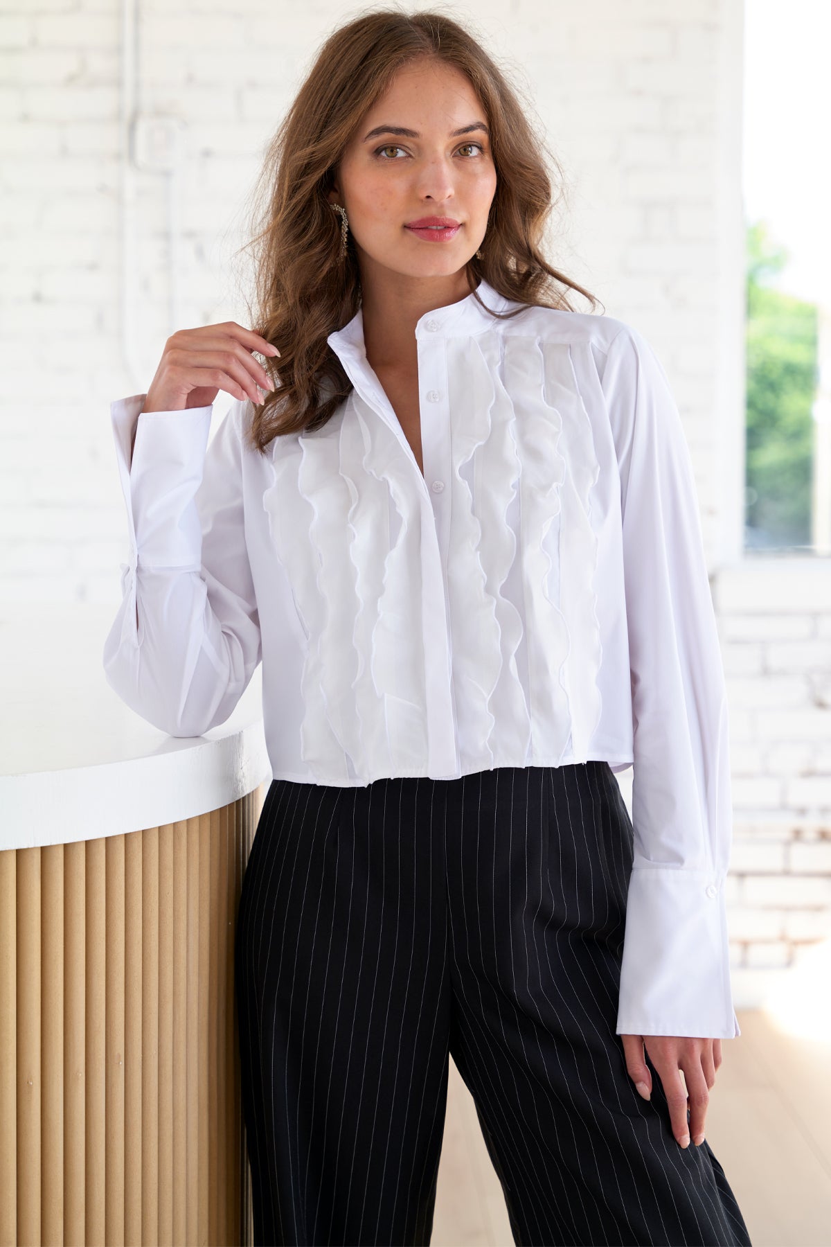 A model wearing the Raffaele long sleeve blouse with a cropped fit, white poplin and silk organza, mandarin collar, and fold-back cuffs in a relaxed fit.