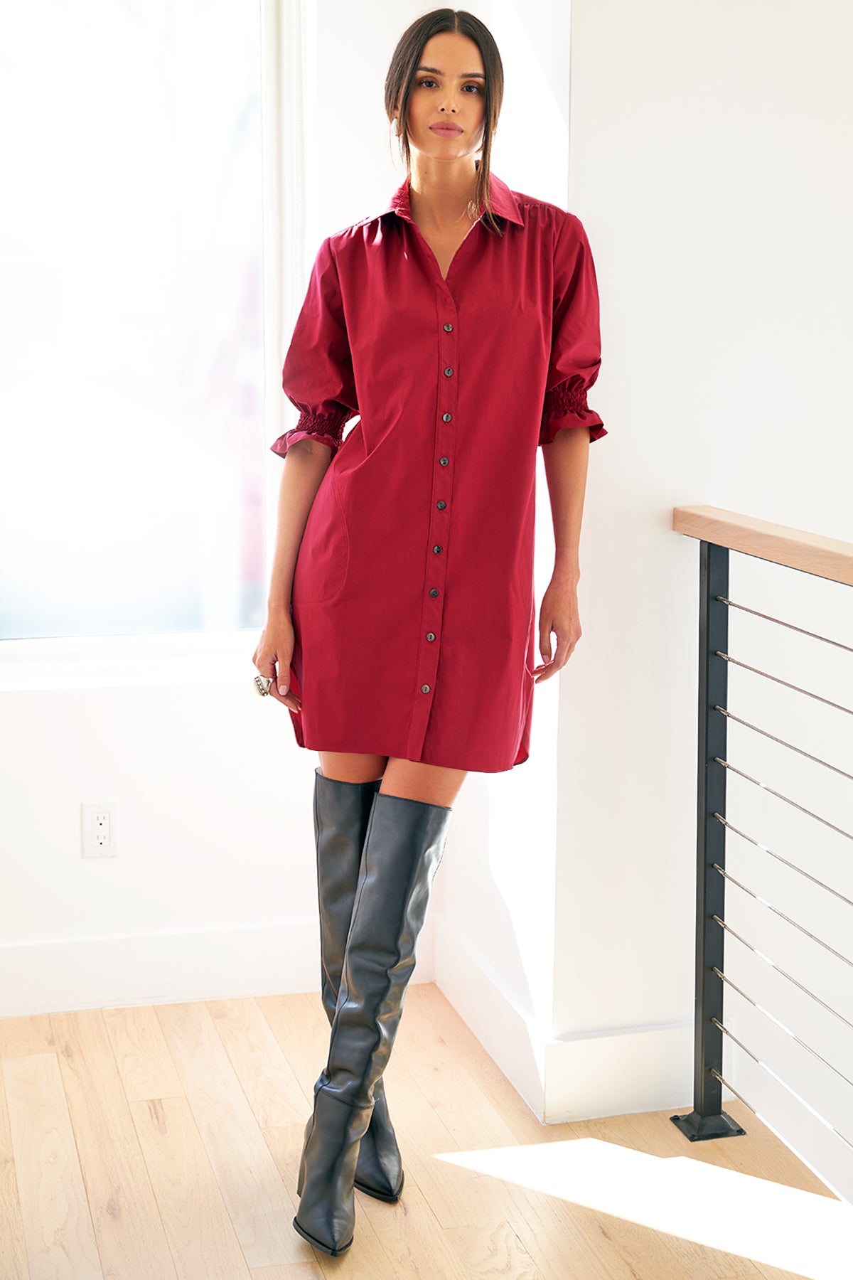 A supermodel wearing the Finley Miller shirtdress, a red weathercloth midi length shirt dress with puff sleeves and a relaxed contour.