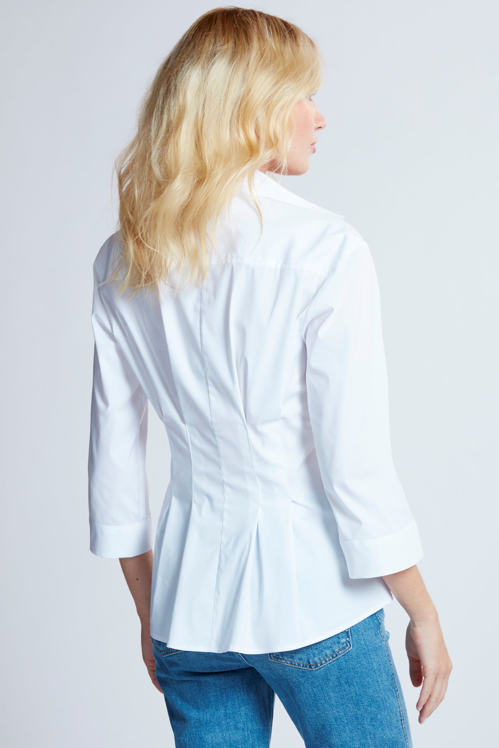 A blonde supermodel wearing the Finley Rocky blouse, a white 3/4 sleeve blouse with a tie front and a tailored fit.