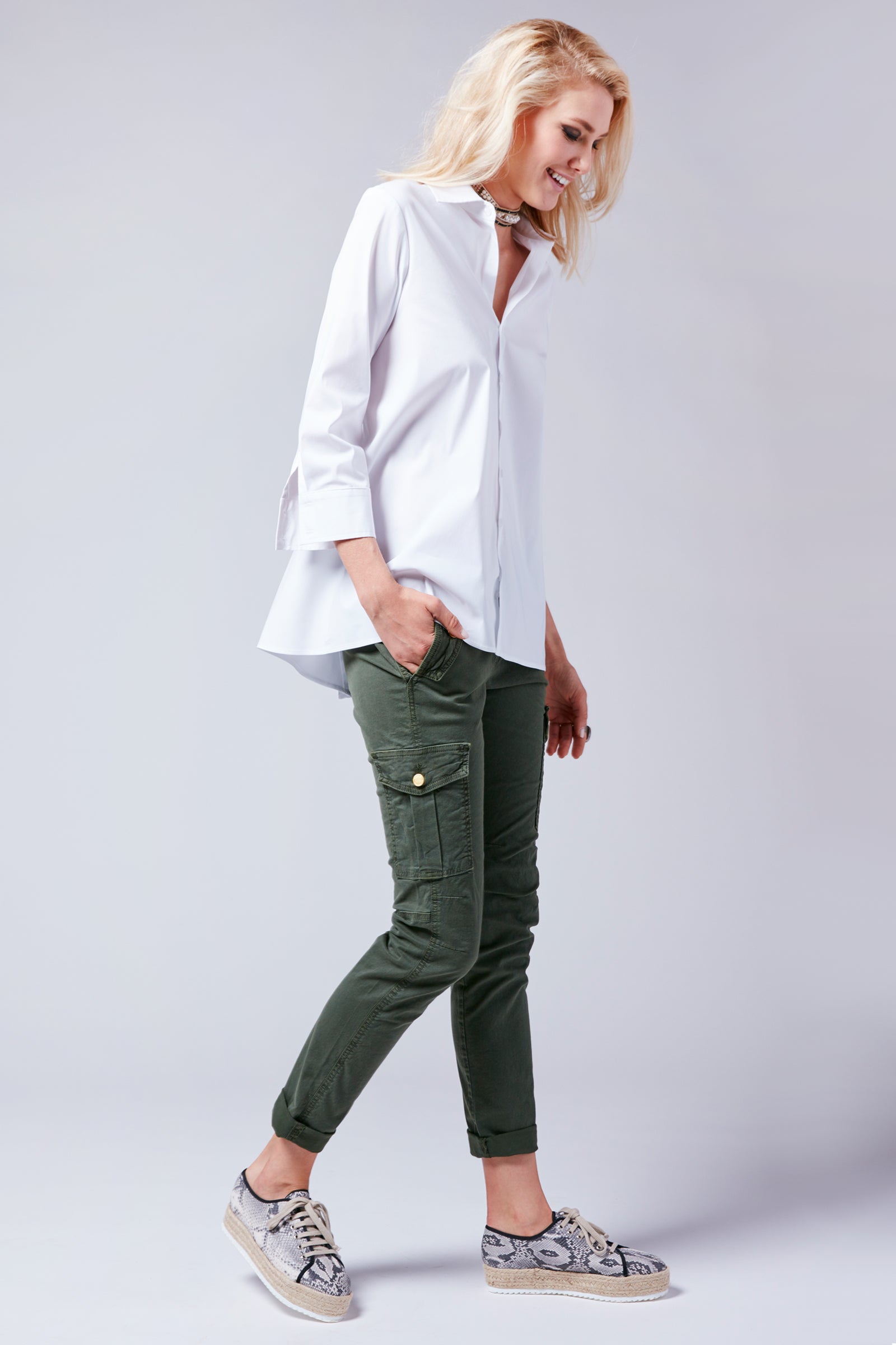 A blonde model wearing the Finley trapeze top, a white 3/4 sleeve button-down casual blouse with an A-line shape and barrel cuff.