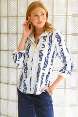 A model wearing the Finley Alex top, a long sleeve button down women's blouse with a front chest pocket and an embroidered geometric navy pattern.