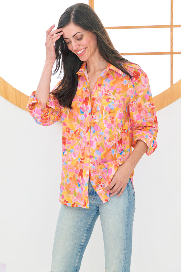 A model wearing the Finley Andie blouse, a cotton button down pink and orange floral blouse with a relaxed contour