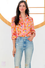 A model wearing the Finley Andie blouse, a cotton button down pink and orange floral blouse with a relaxed contour