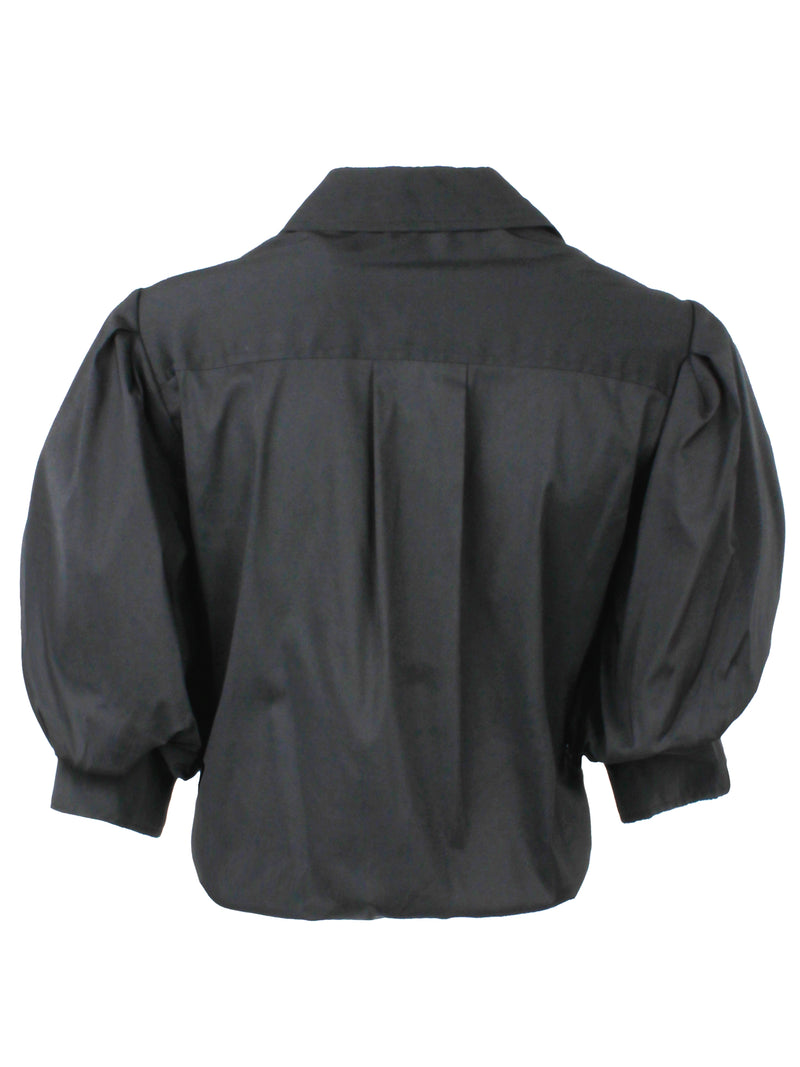 A rear view of the Finley Bomba blouse, a black poplin button front top with a front twist hem and elbow blouson sleeves.