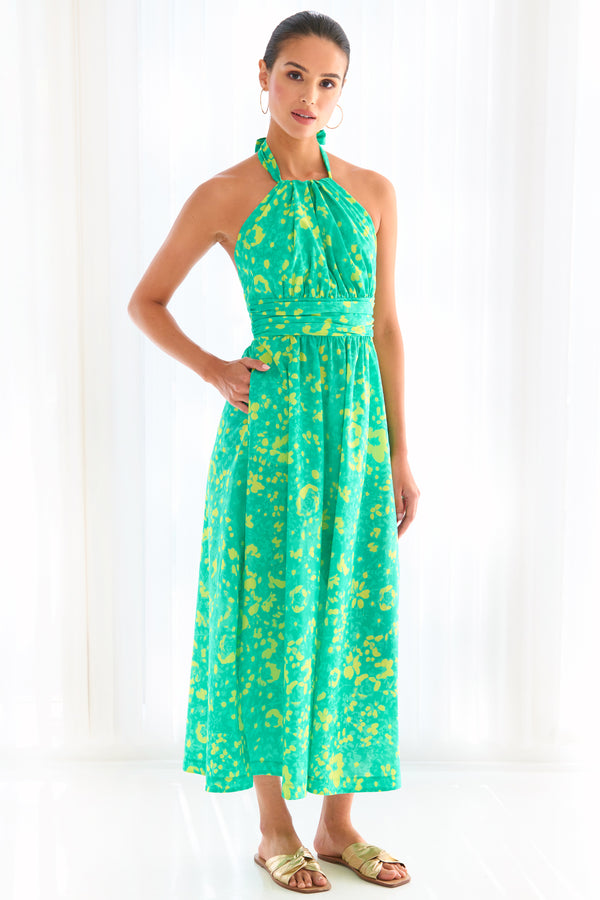 A supermodel wearing the Finley Cameron, a cotton halter top tie front maxi dress with a bright green floral motif.