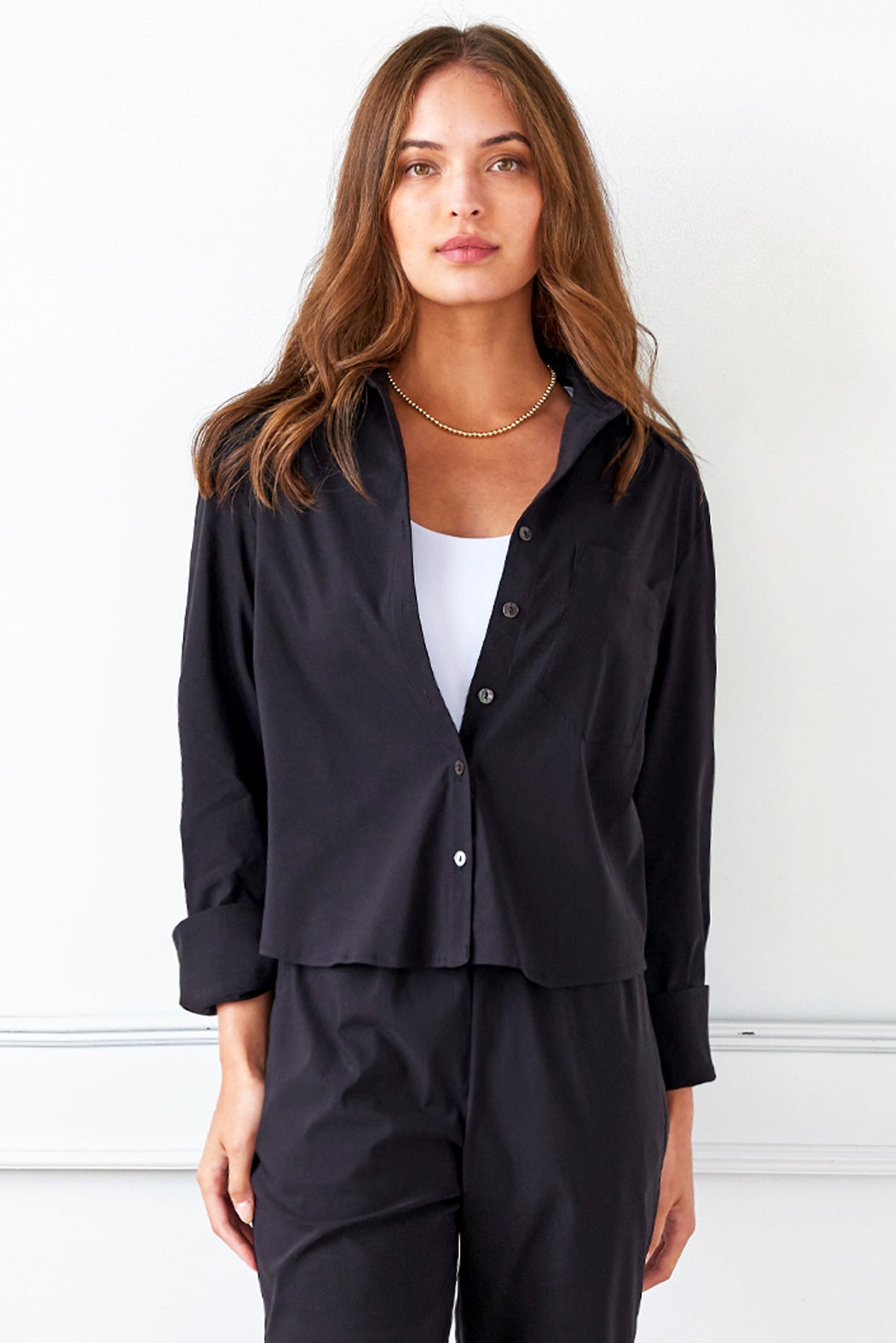 A model wearing the Finley Andie blouse, a black poplin womens blouse with a relaxed cropped shape.