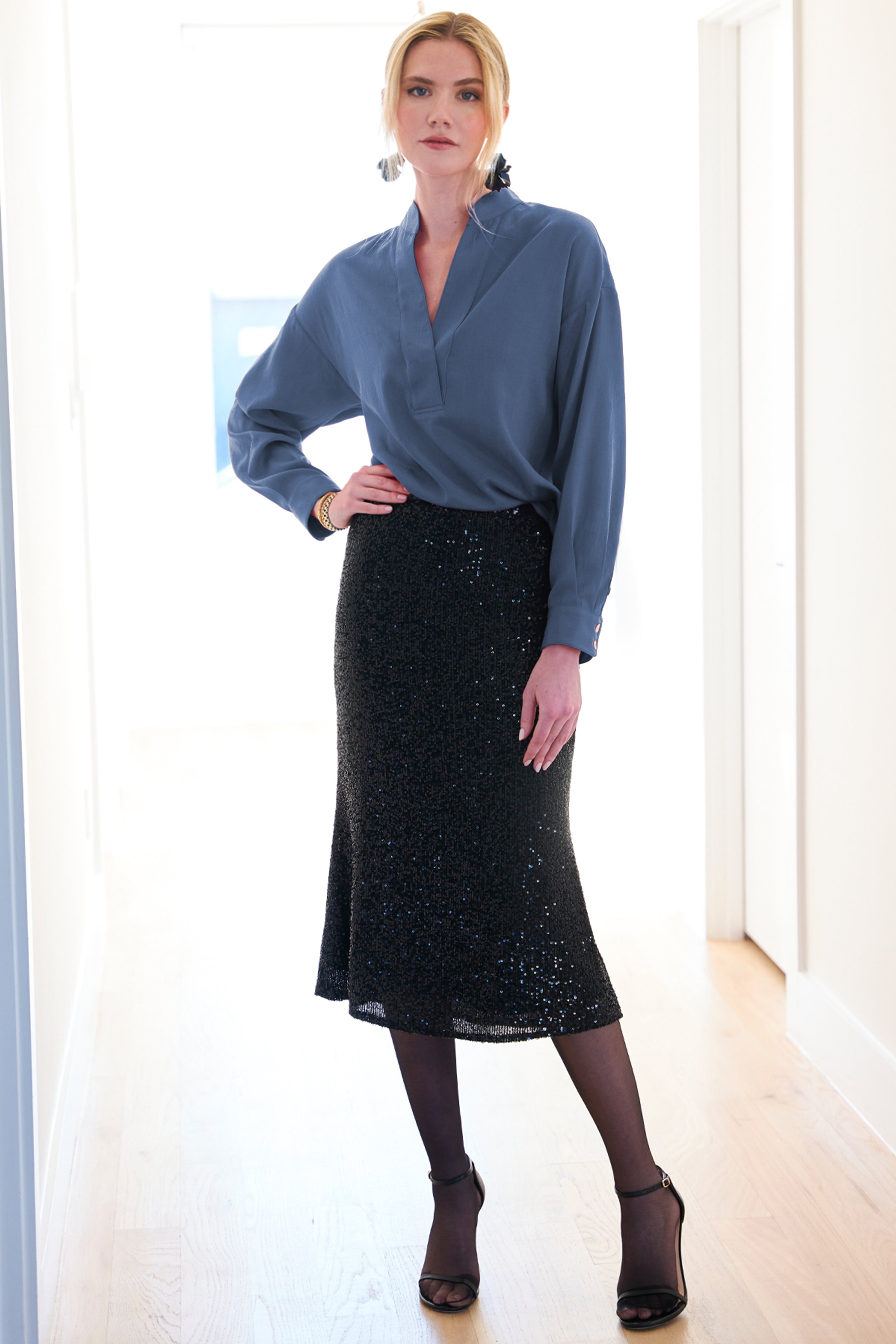 A model wearing the Elsa shirt with a v-neckline, relaxed shape, drop shoulders, and teal cupro cotton.

