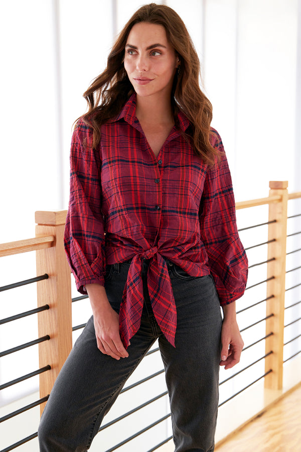 A fashion model wearing Finley Emmy shirt, a red and purple plaid tie front button down women's blouse with a pleated cuff and a relaxed fit.