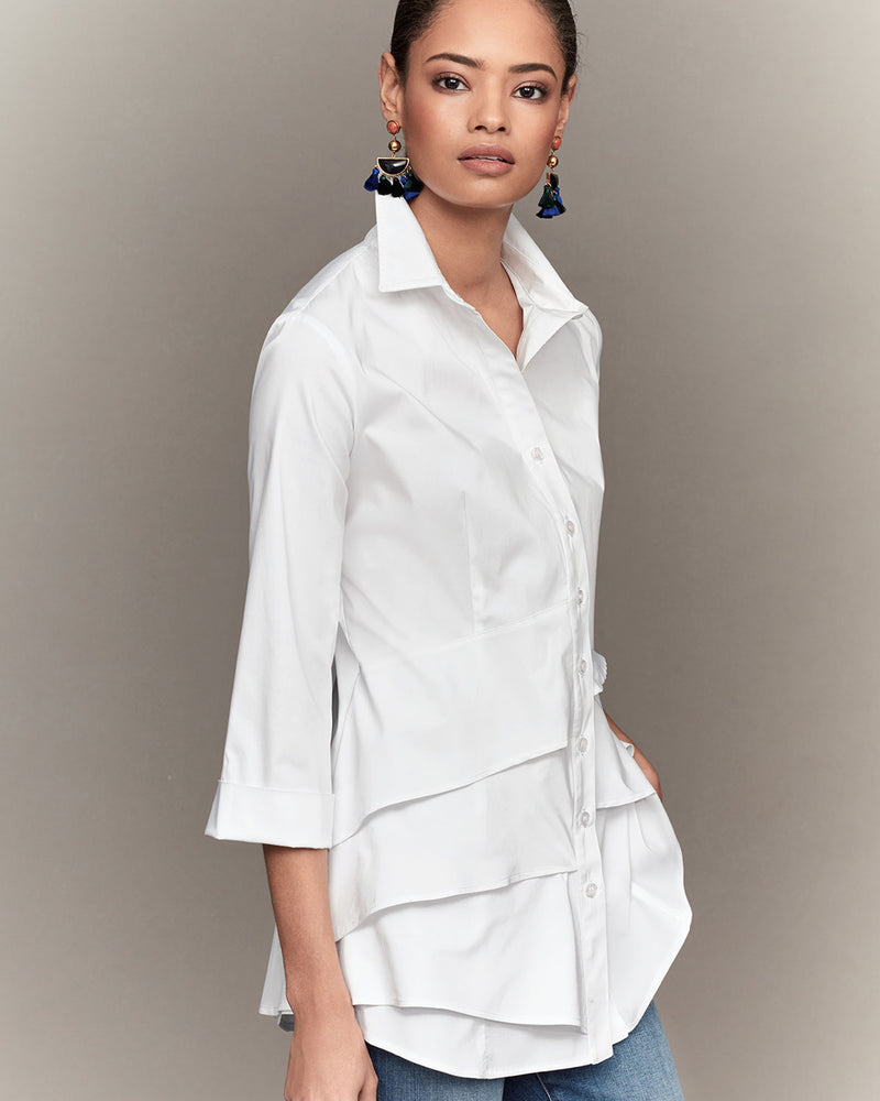A Black model wearing the Finley Jenna blouse, a button down white designer shirt with a ruffle tier hem and a relaxed fit.