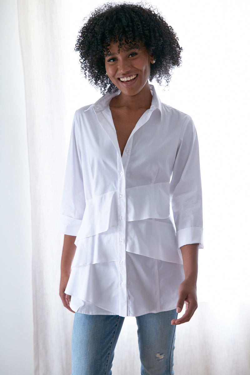 A fashion model wearing the Finley Jenna blouse, a button down white designer shirt with a ruffle tier hem and a relaxed fit.