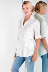 A supermodel wearing the Finley Jenna blouse, a button down white designer shirt with a ruffle tier hem and a relaxed fit.