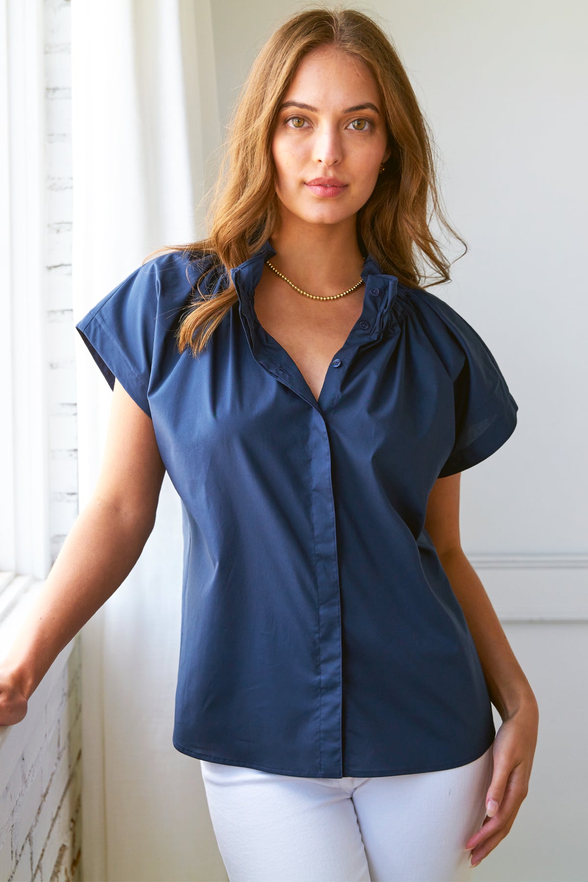 A model view of the Jenny shirt in navy silky poplin, with short sleeves and a stand collar.
