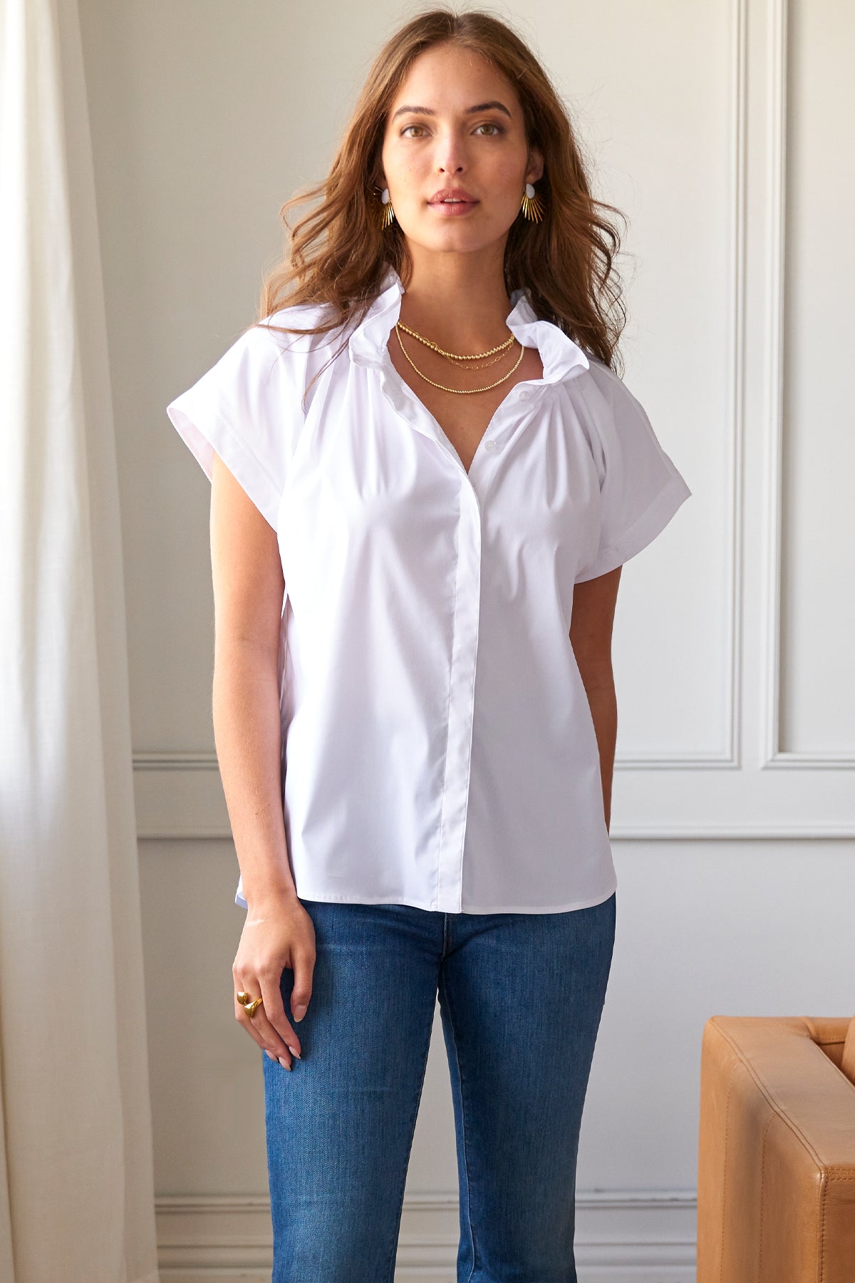 A model wearing the Jenny shirt in white silky poplin, with short sleeves and an effortless design.
