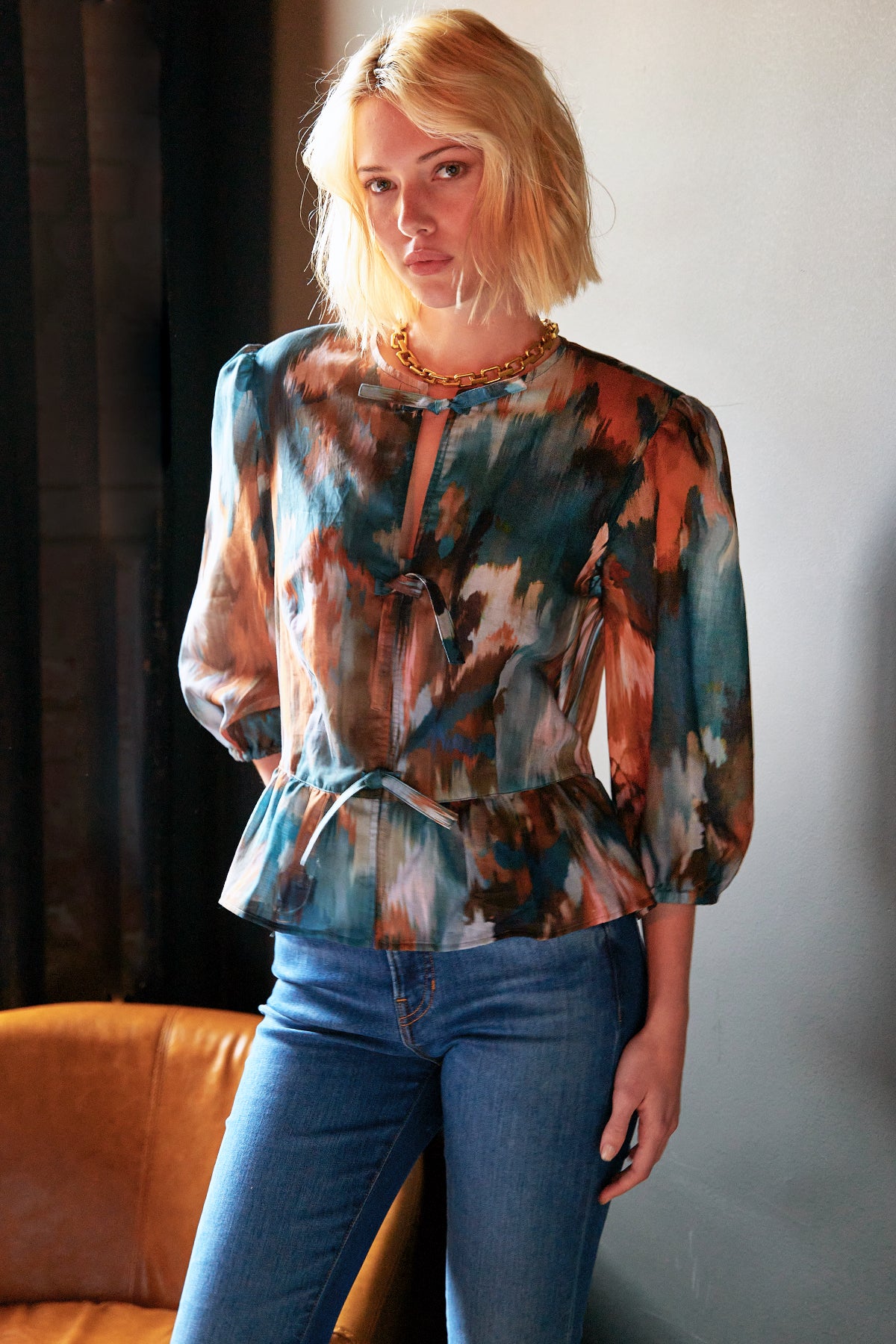 Woman wearing a puff sleeve tie front blouse in green and orange autumn floral pattern