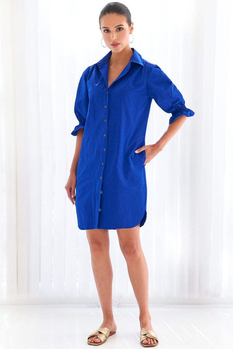 A model wearing the Finley Miller shirt dress, a neon lime green cotton/poly shirt dress with puff short sleeves, pockets, and a relaxed shape.