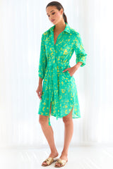 A model wearing the Finley Natalie shirt dress, a tie-front shirt dress with a semi-fitted shape and a bright green and yellow floral print.