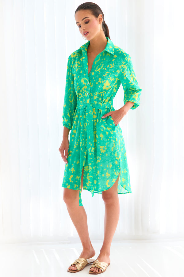 A model wearing the Finley Natalie shirt dress, a tie-front shirt dress with a semi-fitted shape and a bright green and yellow floral print.