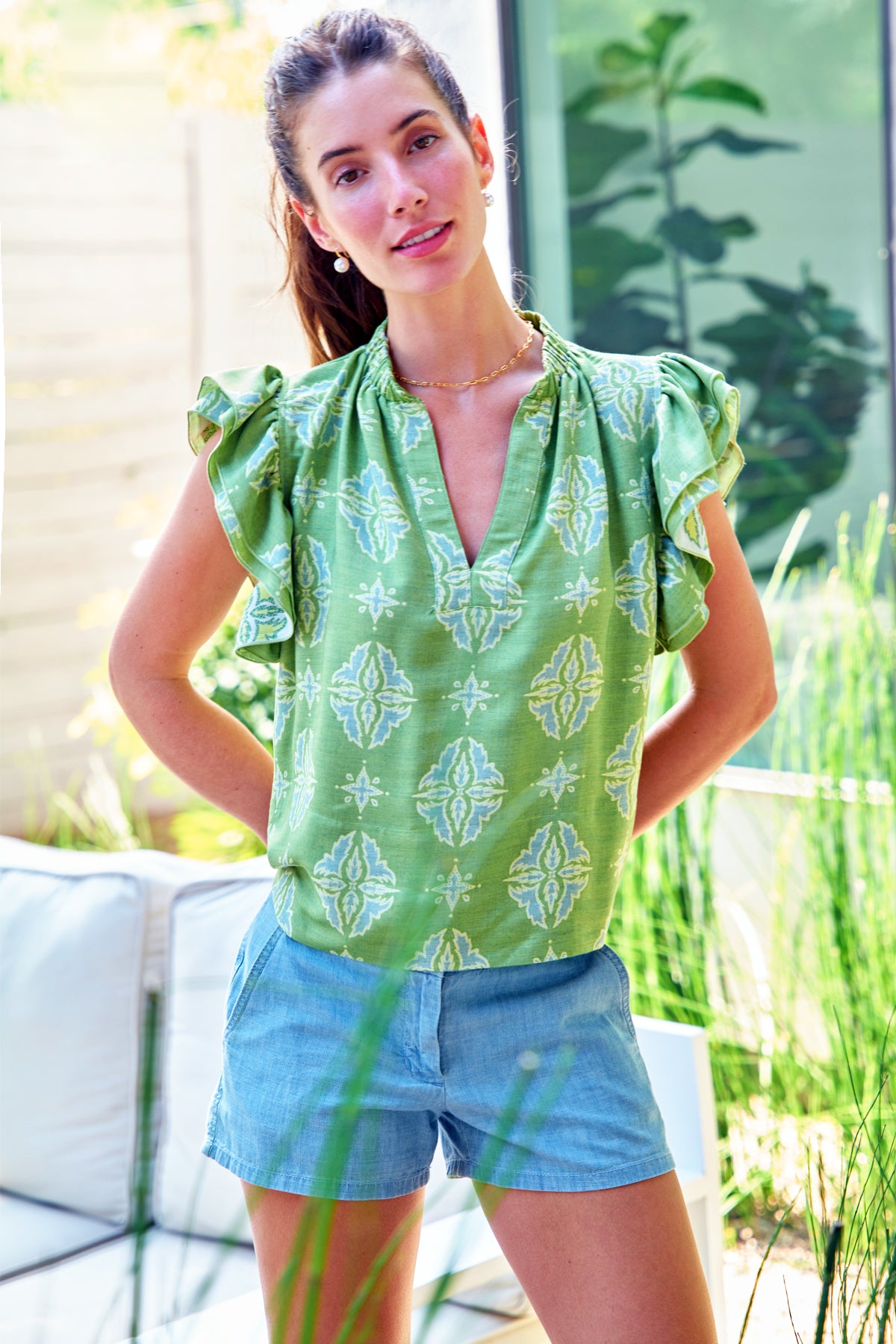 Model wears Finley Remy green and yellow jacquard popover blouse with short ruffle sleeves and V neckline. Boxy fit.
