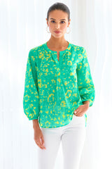 A model wearing the Finley Stephanie top, a v-neck blouse with bracelet sleeves and a bright green and yellow floral print.
