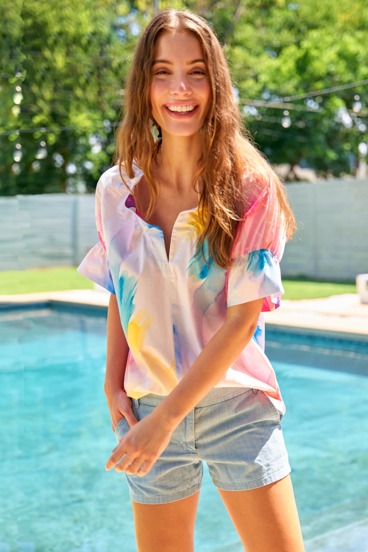 a model front view of the Finley Crosby blouse with a watercolor print, relaxed contour, popover style, v-neck, and ruffle trim.
