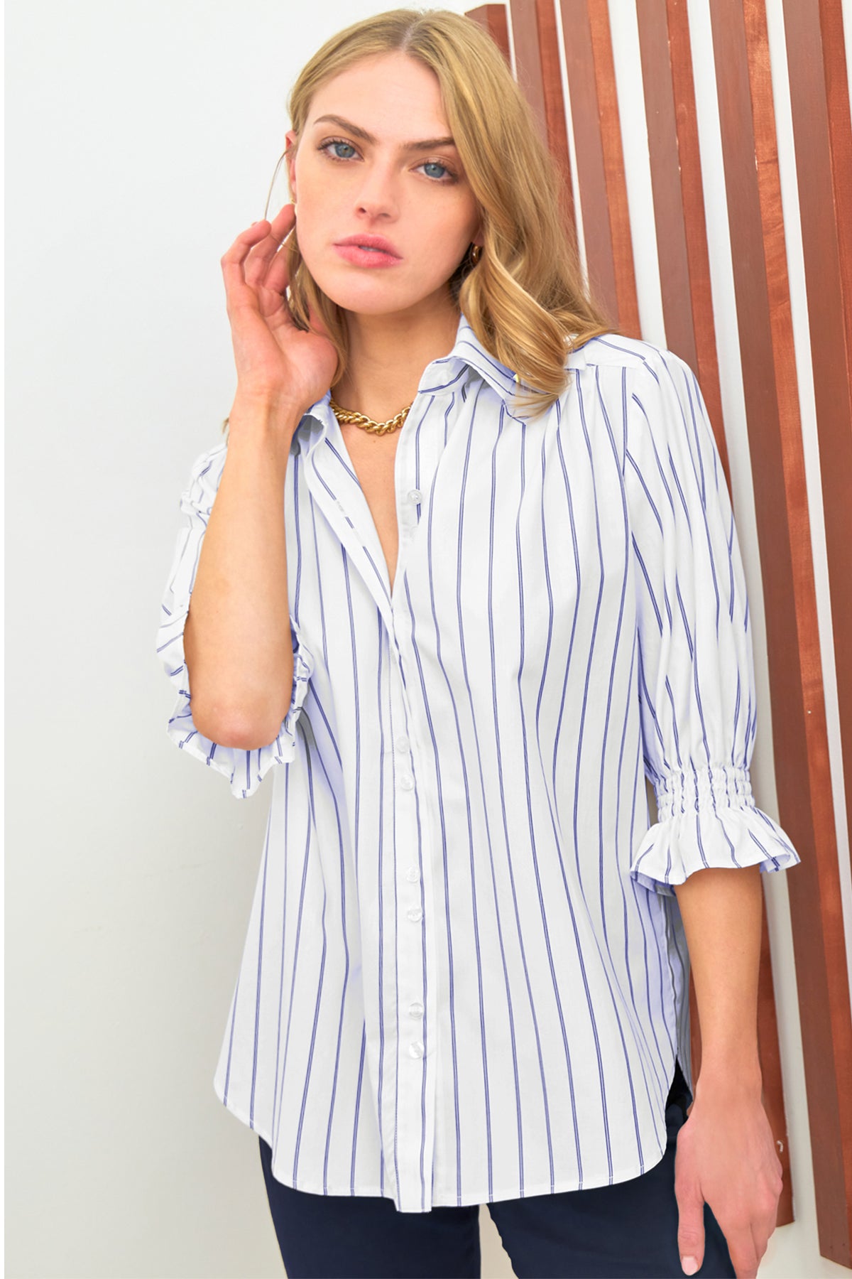 A model wearing the Finley Sirena blouse, a blue pinstripe cotton puff-sleeve blouse with a relaxed shape.