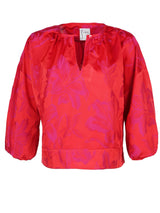The Finley crew top, a pink and red polyester pullover blouse with a 3/4 sleeve and a pink and red floral jacquard pattern.