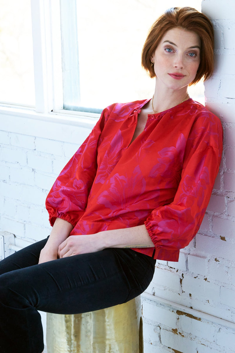 The Finley crew top, a pink and red polyester pullover blouse with a 3/4 sleeve and a pink and red floral jacquard pattern.