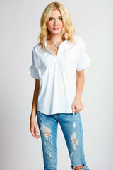 A blonde fashion model wearing the Finley Crosby, a white poplin blouse shirt with a ruffle collar and sleeve detail.