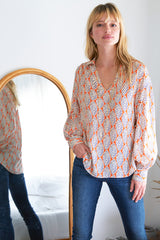 The Finley Davy blouse, a v-neck popover blouse with long puff sleeves and a orange and white leaf pattern.