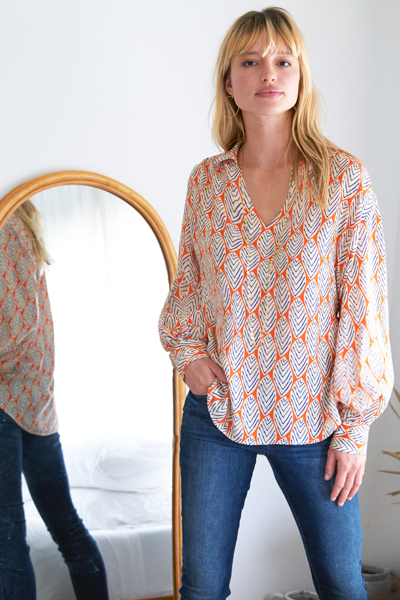 The Finley Davy blouse, a v-neck popover blouse with long puff sleeves and a orange and white leaf pattern.