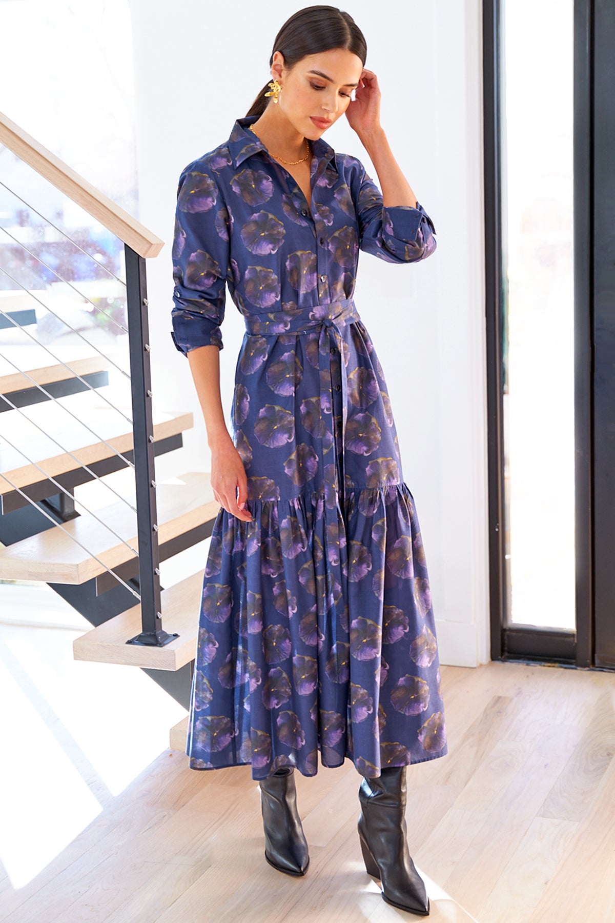 A model wearing the Finley Trisha dress, a cotton maxi tie-front dress with ruffle trim, an A-line silhouette, and a purple floral print.
