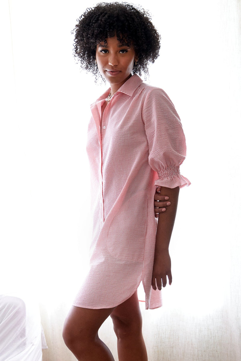 The Finley Miller dress, a coral pink seersucker shirt dress with puff sleeves, a spread collar, and pockets.