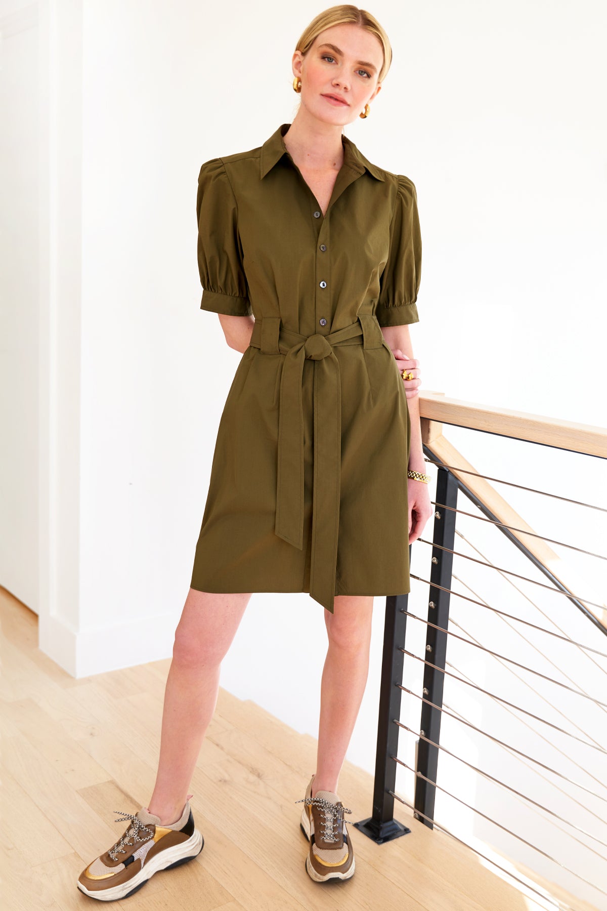 A model wearing the Finley Piper dress, an olive green midi tie-front shirt dress with a fitted shape and short sleeves.