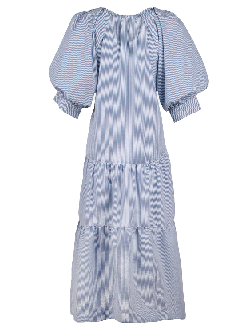 The Finley Paloma dress, a blue seersucker stripe v-neck maxi dress with puff short sleeves and ruffle hem.