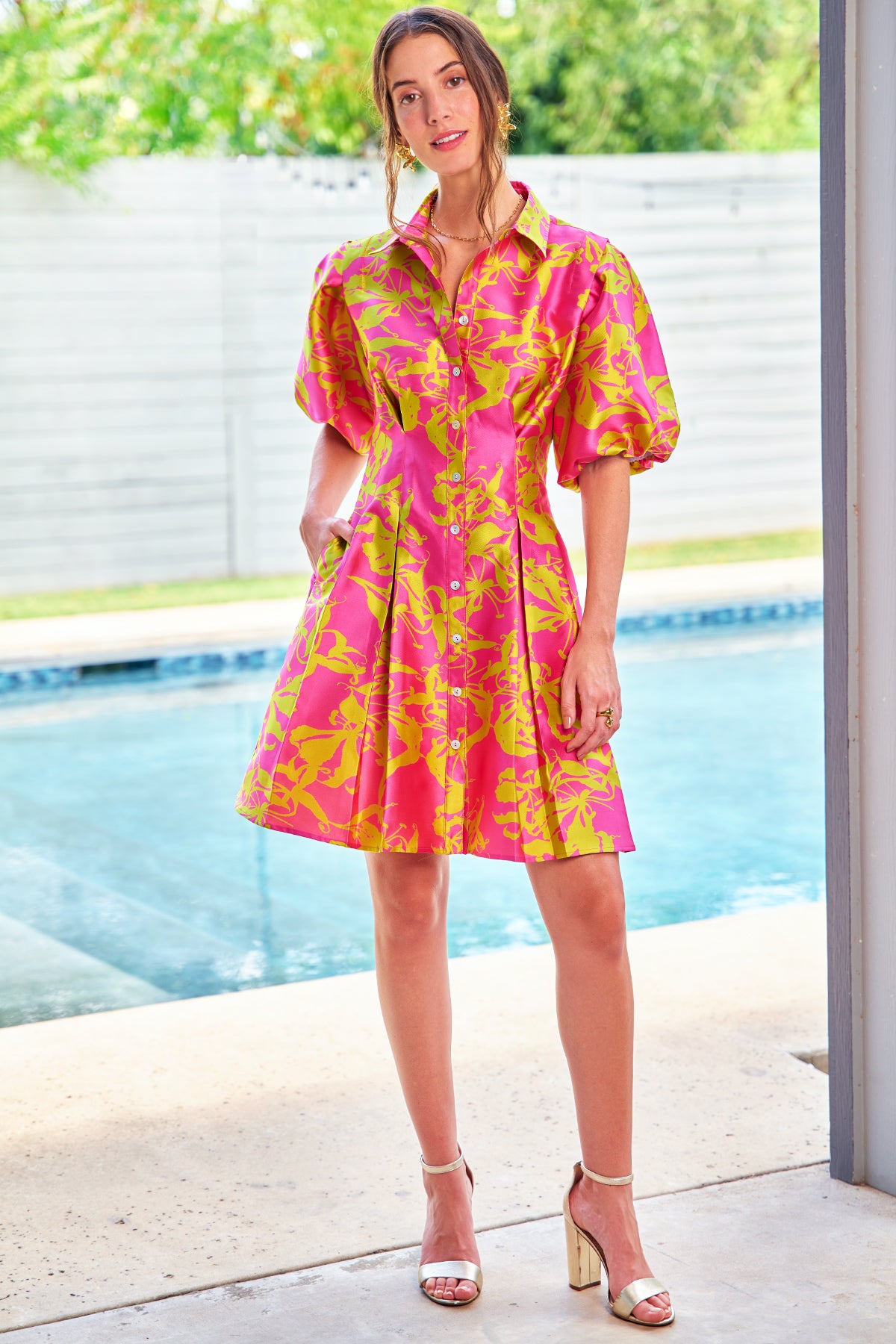 a front model view of the Finley Alicia shirt dress with a pink & yellow floral print, pleated mini length, taffeta fabric, and puff sleeves.
