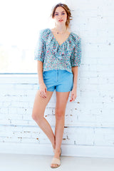A model wearing the Finley Ashleigh top, a cotton voile pullover blouse with a relaxed shape and a green and white floral print.