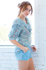 A model wearing the Finley Ashleigh top, a cotton voile pullover blouse with a relaxed shape and a green and white floral print.