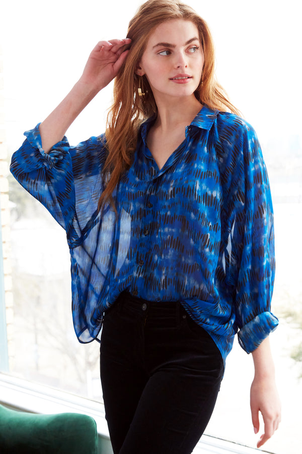 A model wearing the Finley Dylan Dolman shirt, a chiffon blouse with a relaxed fit and an abstract blue and black pattern.